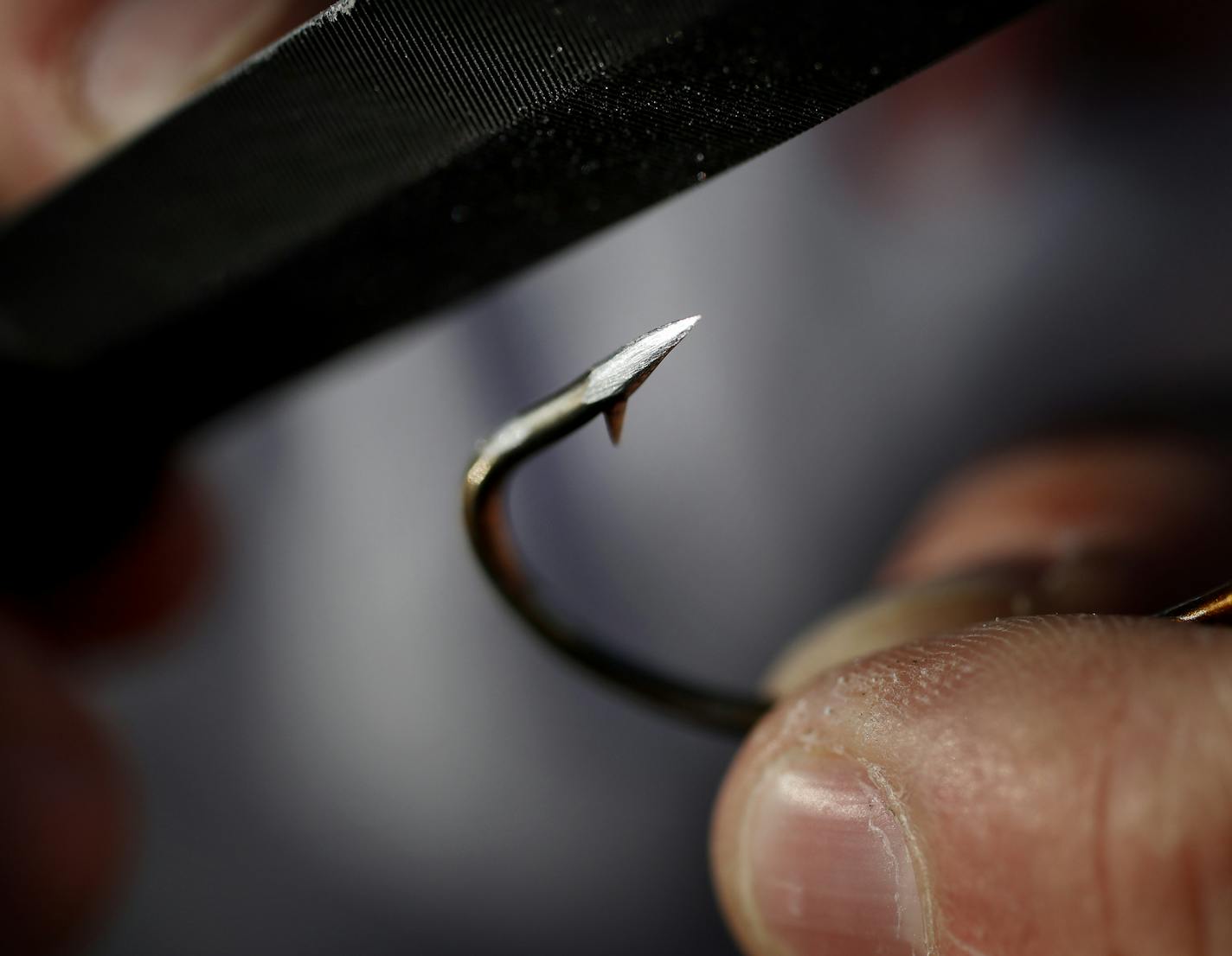 Fishing guide Travis Frank sharpened the hooks on a lure. Frank sharpens his hooks every time before he fishes for Muskie. ] CARLOS GONZALEZ cgonzalez@startribune.com - June 8, 2016, Waconia, MN, Outdoors Weekend, Meeting Muskie angler Travis Frank to fish Lake Waconia