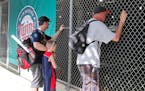 Baseball fans look through a fence at Hammond Stadium after a game between the Twins and the Orioles was canceled on March 12. MLB suspended spring tr