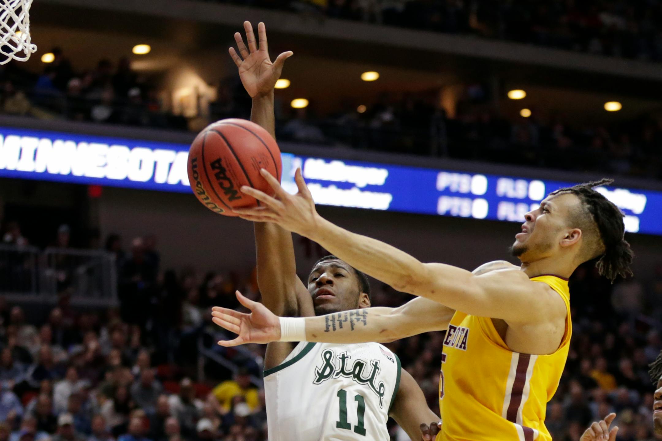 Minnesota's Amir Coffey, right, goes to the basket against Michigan State's Aaron Henry (11) during the first half of a second round men's college basketball game in the NCAA Tournament, in Des Moines, Iowa, Saturday, March 23, 2019. (AP Photo/Nati Harnik)