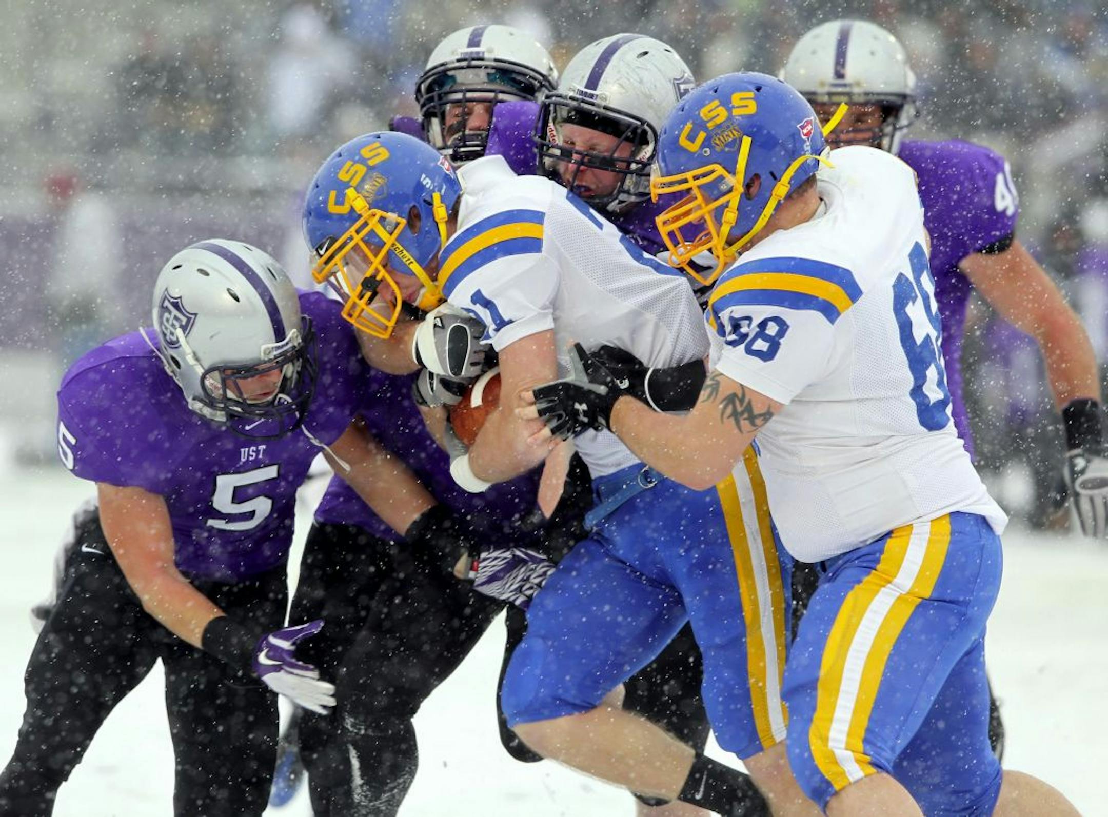 St. Scholastica's Travis Nehowig (21) attempts to push through the St. Thomas defense during the Saints' NCAA Division III playoff game against the Tommies at the University of St. Thomas in St. Paul November 19, 2011. St. Thomas won, 48-2.