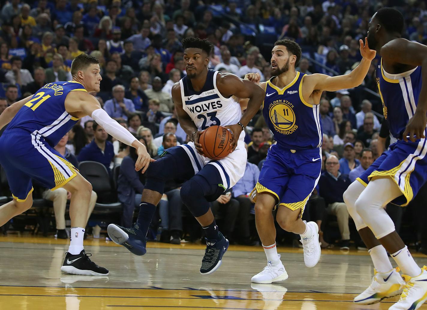 The Timberwolves' Jimmy Butler (23) drives the ball between Golden State Warriors' Jonas Jerebko, left, and Klay Thompson