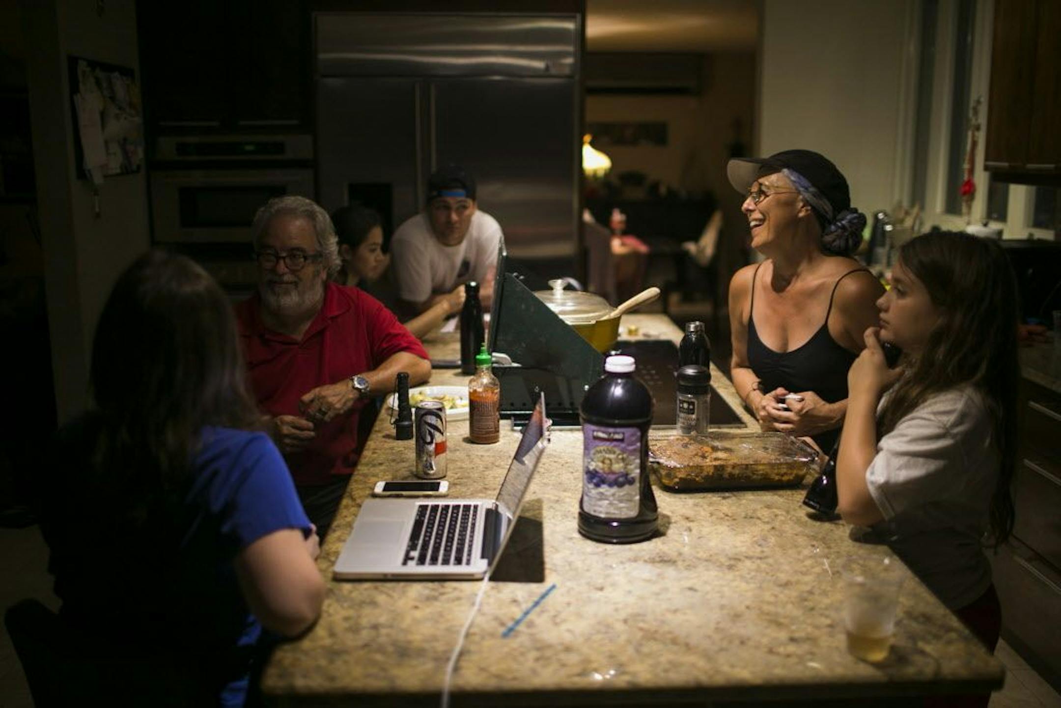 Members of the Rodriguez-Martinez family around a light powered by generator, at Maria Julia Martinez� home in Guaynabo, Puerto Rico, Oct. 10, 2017. Using generators, rationing and even bonfires, Puerto Ricans have had to get creative to survive weeks without power or regular water and food after Hurricane Maria.