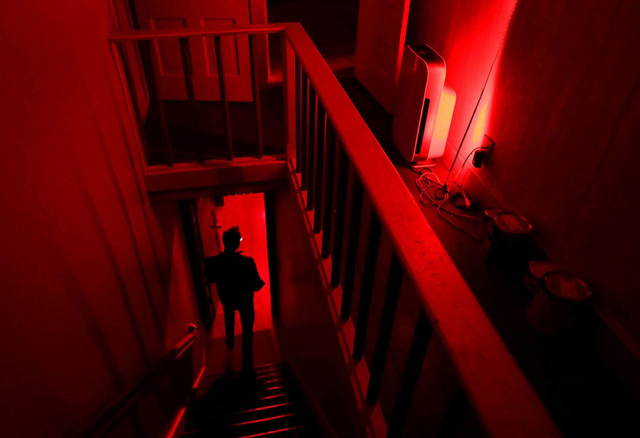 Biohacker Thaddeus Owen takes the stairs to the first floor in the family's home, bathed in red light each day.