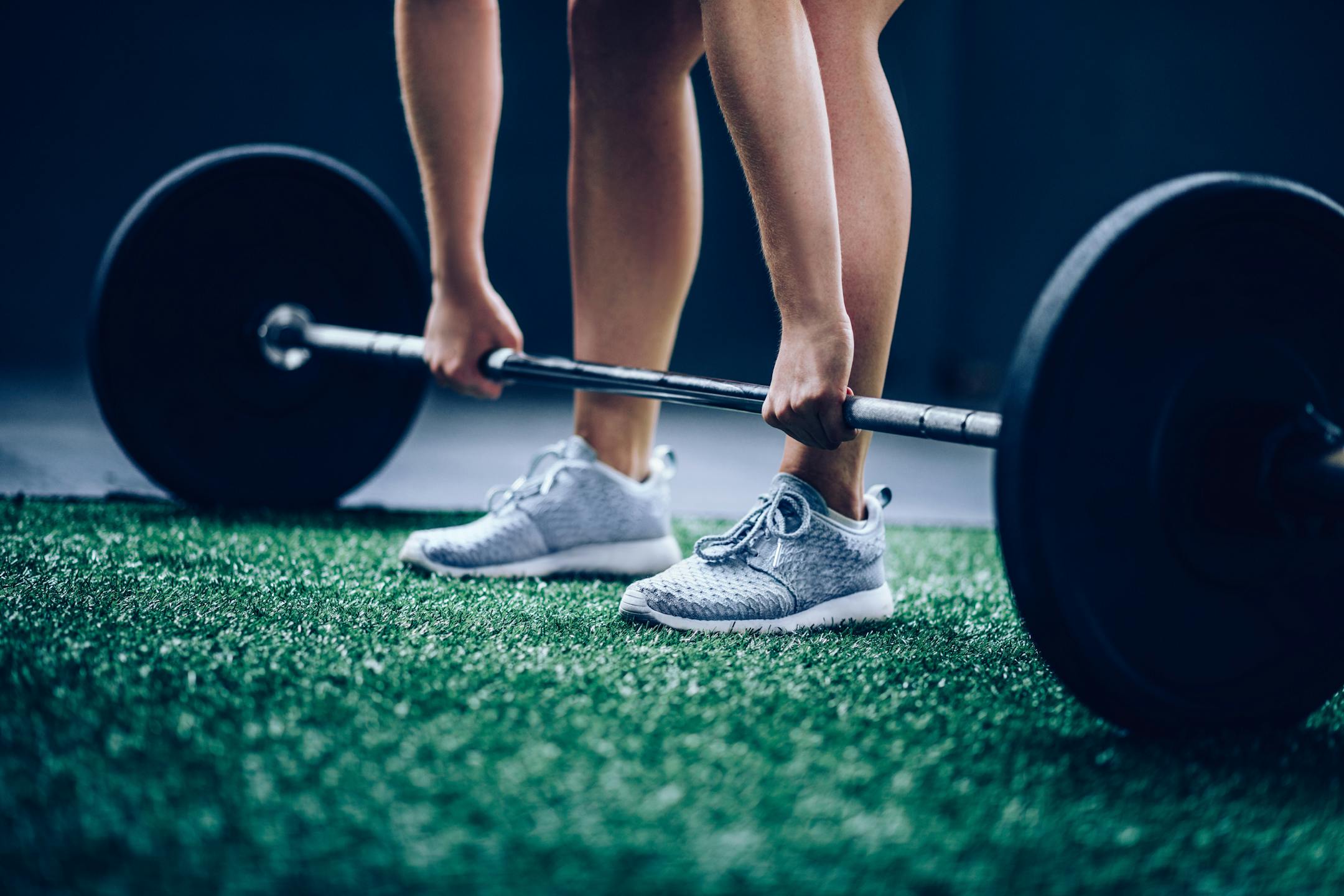 Fit Girl picking up heavy barbell with weights for workout