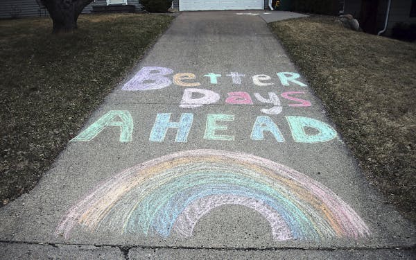 A chalk message and rainbow adorn a driveway with a positive message in the fight against the coronavirus at a Bloomington, Minn. home Wednesday, Apri