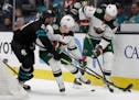 San Jose Sharks' Brandon Davidson, left, fights for the puck with Minnesota Wild forward Ryan Donato (6) and Mikko Koivu, right, in the second period 