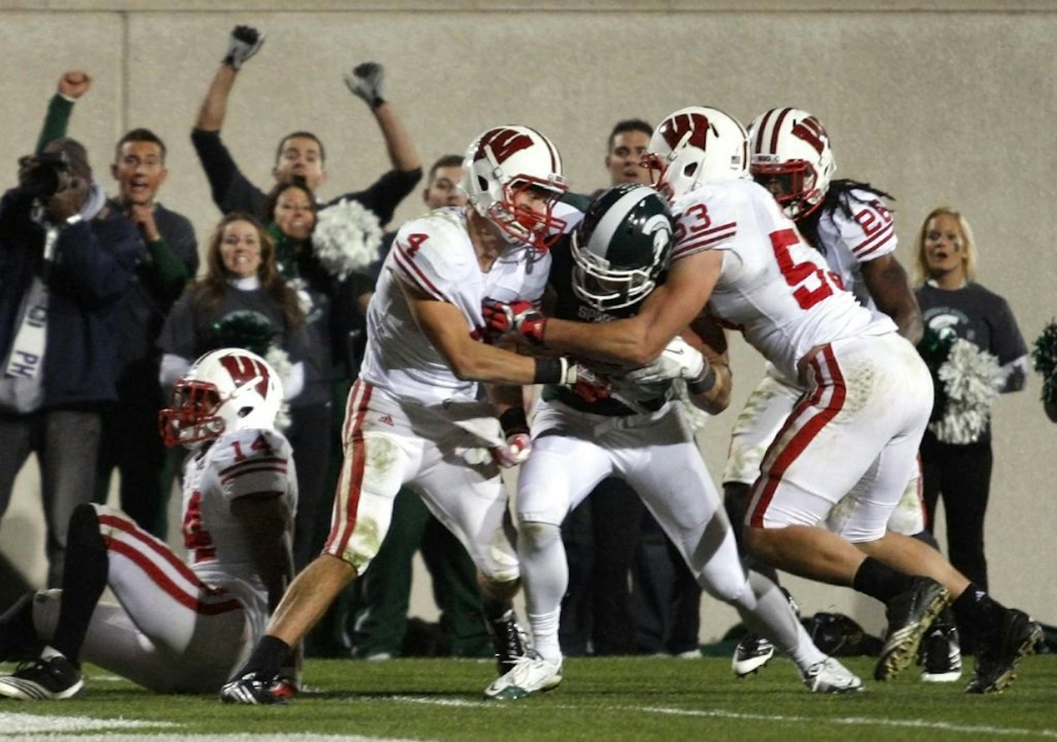 FILE - In this Oct. 22, 2011, file photo, Michigan State's Keith Nichol, center, pushes his way toward the goal line to score a touchdown after catching a tipped-hail Mary pass as Wisconsin's Jared Abbrederis (4) and Mike Taylor (53) defend, as Marcus Cromartie (14) and Adam Hampton (26) look on, as time expires in the fourth quarter of an NCAA college football game in East Lansing, Mich. Nichol surged forward to break the plane of the goal to give Michigan State a 37-31 win.