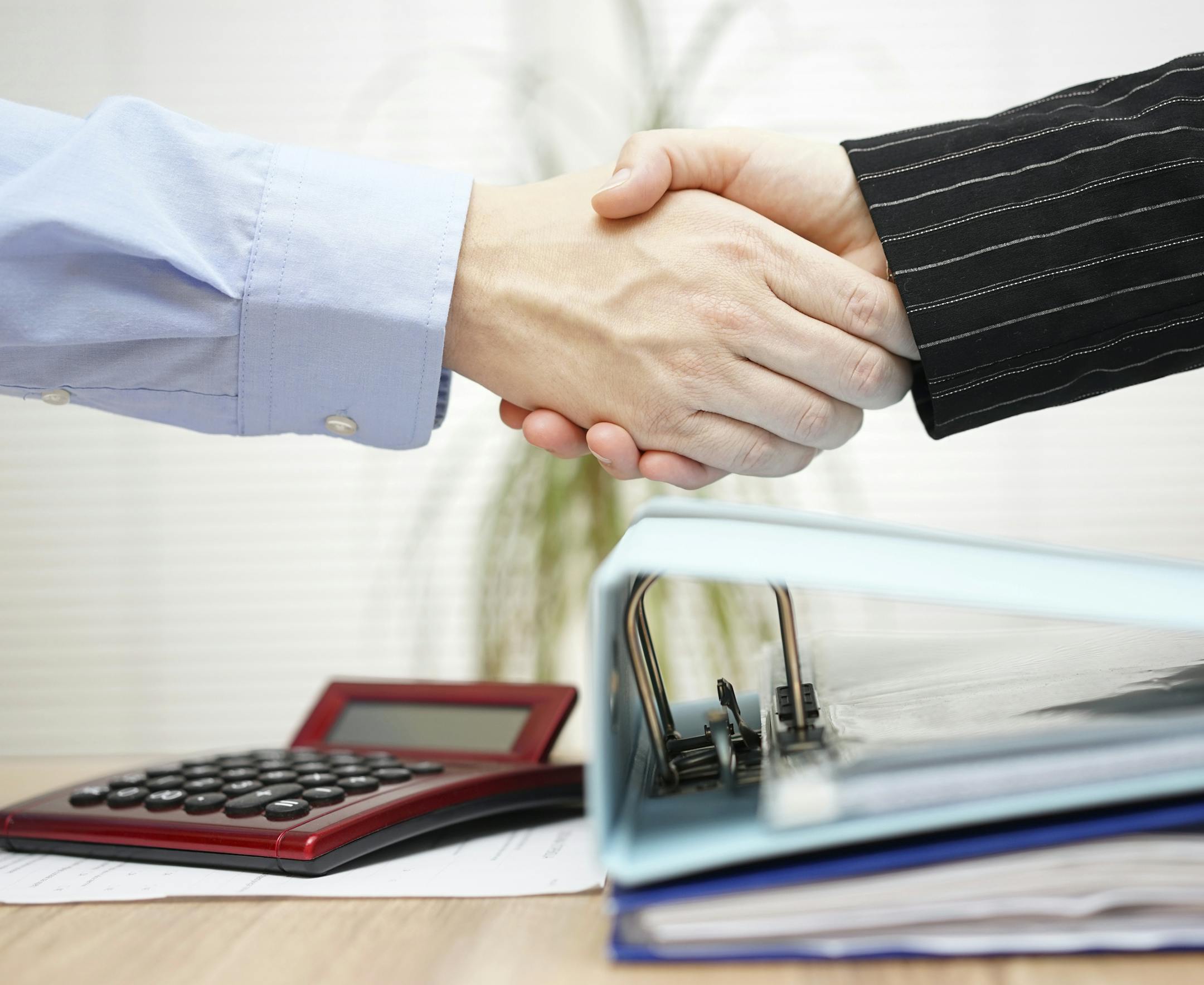 businessman and businesswoman are handshaking over binders