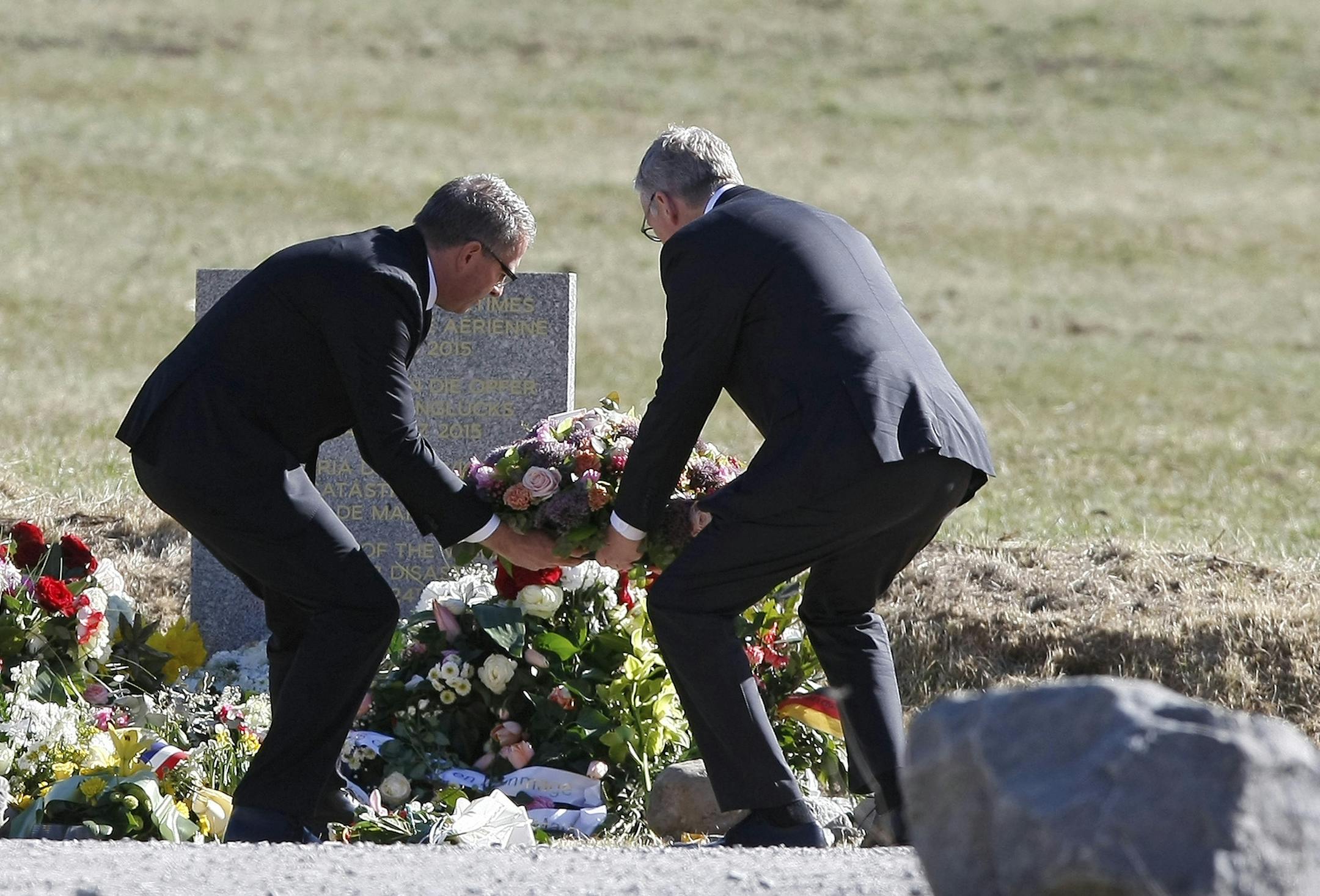 CEO of Germanwings Thomas Winkelmann and Lufthansa CEO Carsten Spohr, left, lay a wreath of flowers at a stone slab erected as a monument in memory of the victims, near the site of the Germanwings jet crash, in Le Vernet, France, Wednesday, April 1, 2015. The heads of Lufthansa and its low-cost airline Germanwings are visiting the site of the crash that killed 150 people amid mounting questions about the co-pilot and how much his employers knew about his mental health. (AP Photo/Claude Paris)