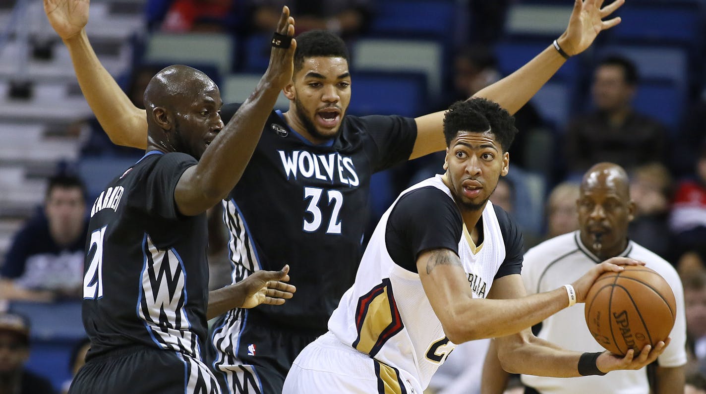 New Orleans Pelicans forward Anthony Davis, right, looks to pass against Minnesota Timberwolves center Karl-Anthony Towns (32) and forward Kevin Garnett (21) during the first half of an NBA basketball game Tuesday, Jan. 19, 2016, in New Orleans. (AP Photo/Jonathan Bachman)