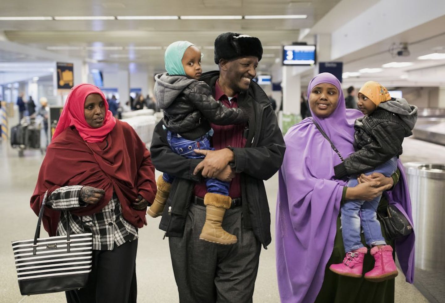 Mohamed lye carries his 2-year old daughter Nafiso, with his wife Saido Ahmed Abdille, left, at Minneapolis-Saint Paul International Airport near Bloomington, Minn., after arriving from Amsterdam on Sunday, Feb. 5, 2017. His 4-year-old daughter Nimo, was carried by family friend Abdinasir Abdulahi.