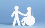 Wheelchair bound person and helper - paper cutouts.
