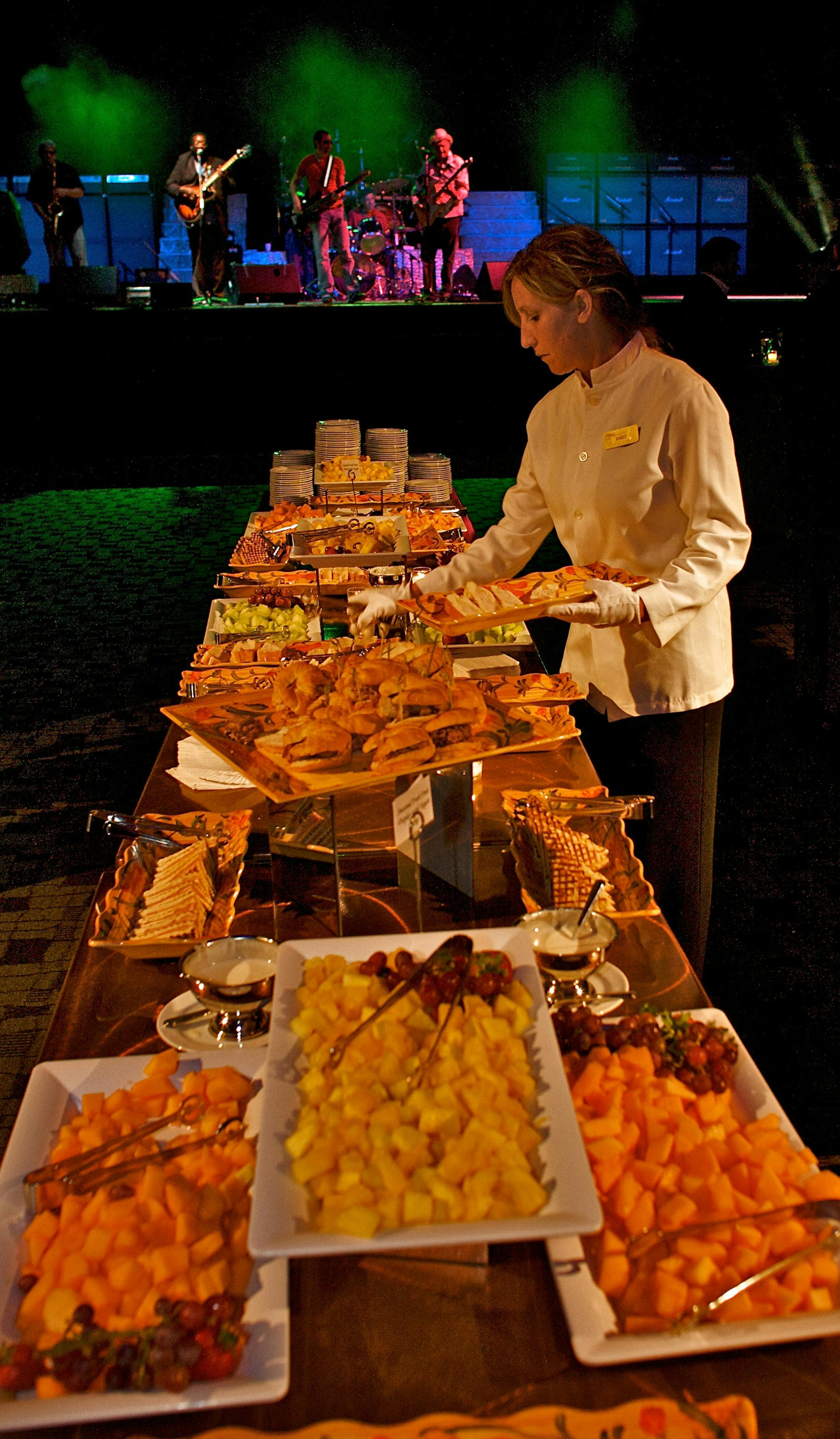Aimee Lundberg, banquet server, freshens up one of the food tables at the AgNite banquet while the Lamont Cranston Band plays in the background.