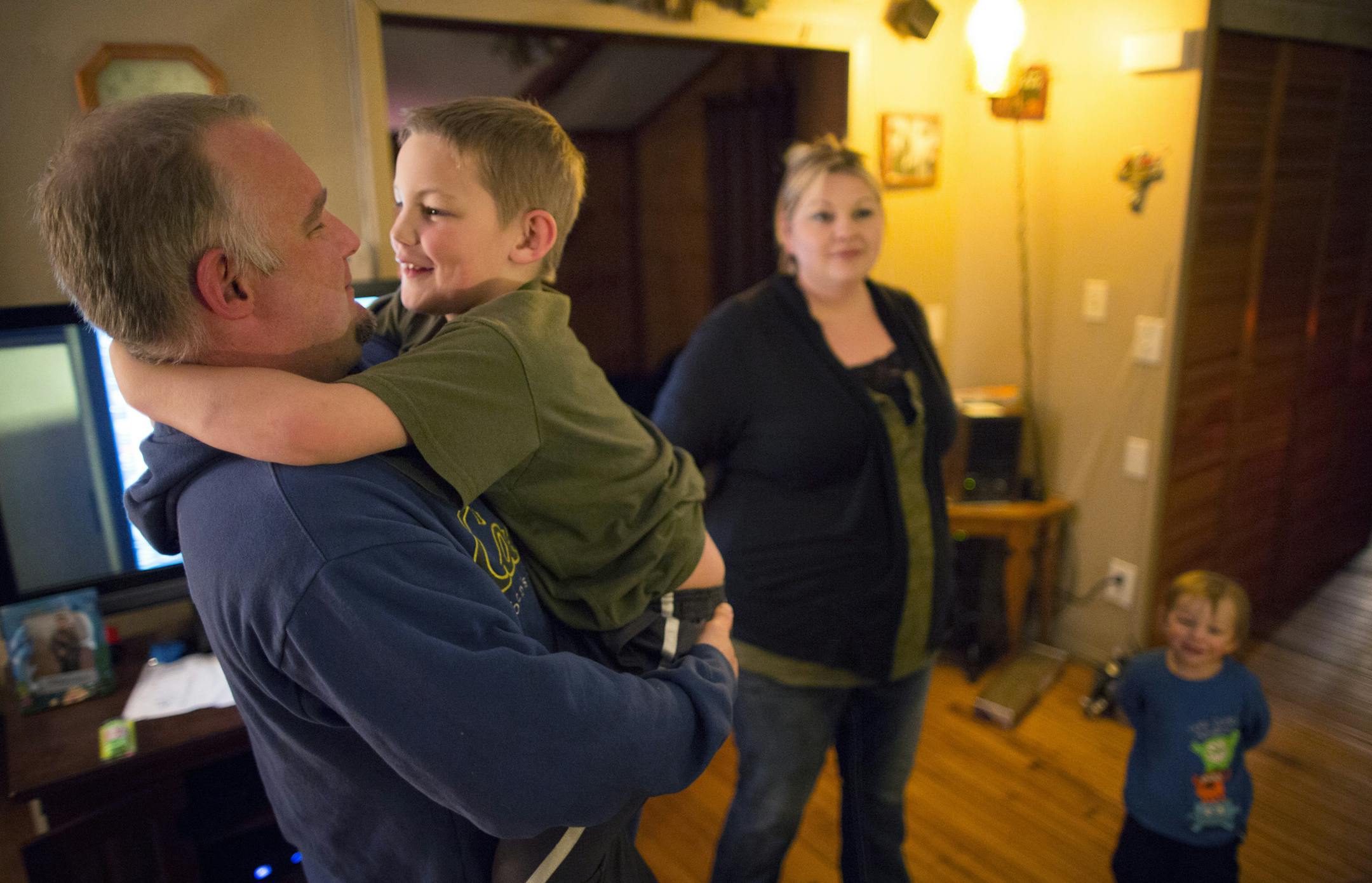 Sean Honeycutt (left) fears he will be laid off and is retraining himself to keep himself marketable. Here, Honeycutt gets a hug from his son Jacob, 8, at their home in Goodland. Girlfriend Kayla and son Kacey, 2. at right. United States Steel Corp. plans to temporarily idle part of its Minntac plant in Mountain Iron, Minn. on June 1. ] BRIAN PETERSON ï brianp@startribune.com Goodland, MN - 4/6/2015 ORG XMIT: MIN1504071942382932