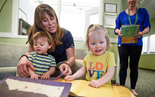 Diane Gates, 44, of Minnetonka, looks at books with her twins, Theo and Haley Gates-Buss, both 22 months old, at Bright Horizons, the on-site child ca