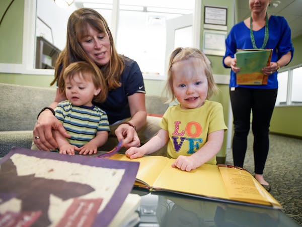 Diane Gates, 44, of Minnetonka, looks at books with her twins, Theo and Haley Gates-Buss, both 22 months old, at Bright Horizons, the on-site child ca