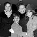 FILE - In this Dec. 29, 1964 file photo, singer-actress Judy Garland greets her son Joseph, 9, and daughter Lorna, 12, after they arrive from California at New York's Kennedy International Airport, in New York. Garland's elder daughter Liza Minnelli poses with them at left. Judy Garland has been laid to rest in a mausoleum named for her at Hollywood Forever Cemetery. A spokeswoman for Garland’s estate has said her family and friends held a private memorial service for the late actress on