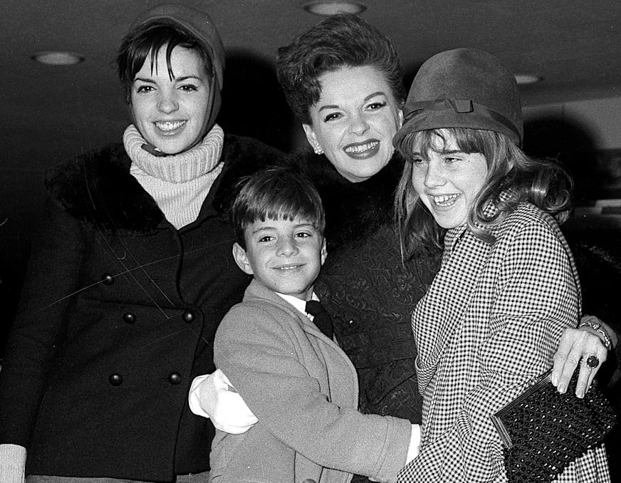 FILE - In this Dec. 29, 1964 file photo, singer-actress Judy Garland greets her son Joseph, 9, and daughter Lorna, 12, after they arrive from California at New York's Kennedy International Airport, in New York. Garland's elder daughter Liza Minnelli poses with them at left. Judy Garland has been laid to rest in a mausoleum named for her at Hollywood Forever Cemetery. A spokeswoman for Garland’s estate has said her family and friends held a private memorial service for the late actress on
