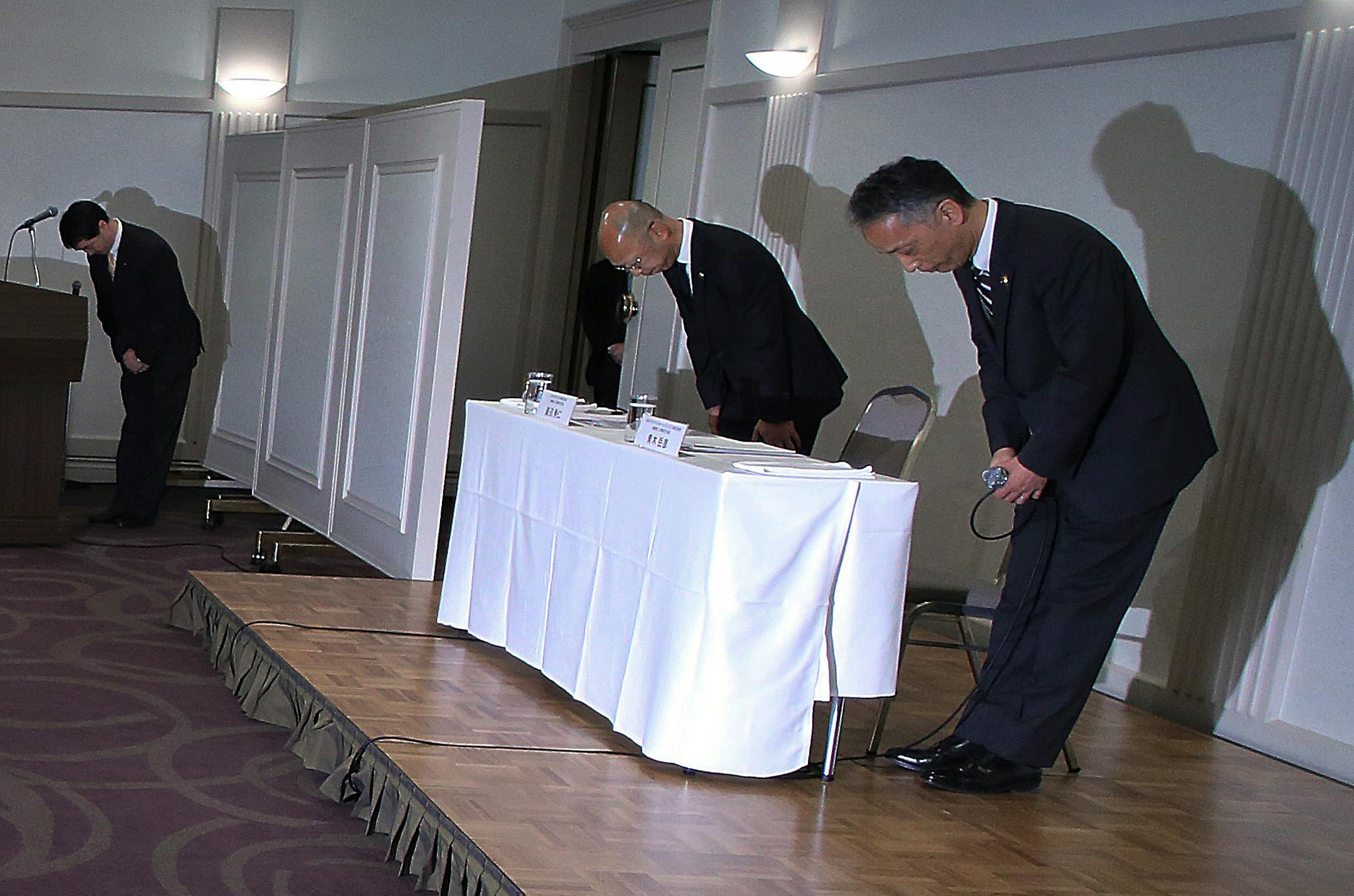 McDonald's Holdings Company Senior Vice President Takehiko Aoki, right, and McDonald's Company Ltd. Senior Vice President Hidehito Hishinuma, center, bow at the start of a press conference in Tokyo, Wednesday, Jan. 7, 2015. McDonald's Corp. officials in Japan bowed deeply Wednesday to apologize for a human tooth, plastic pieces and other objects found in the burger chain's food, highlighting how consumers here are both loving and hating the popular fast-food eatery. (AP Photo/Eugene Hoshiko)