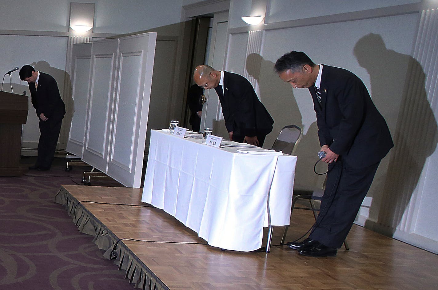 McDonald's Holdings Company Senior Vice President Takehiko Aoki, right, and McDonald's Company Ltd. Senior Vice President Hidehito Hishinuma, center, bow at the start of a press conference in Tokyo, Wednesday, Jan. 7, 2015. McDonald's Corp. officials in Japan bowed deeply Wednesday to apologize for a human tooth, plastic pieces and other objects found in the burger chain's food, highlighting how consumers here are both loving and hating the popular fast-food eatery. (AP Photo/Eugene Hoshiko)
