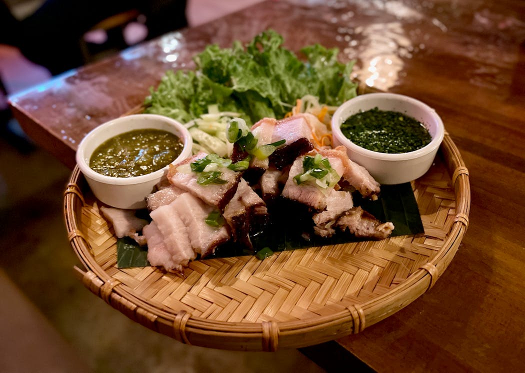 Pork belly, cooked until tender with a super crispy skin, is served with lettuce wrap accompaniments and two green sauces.