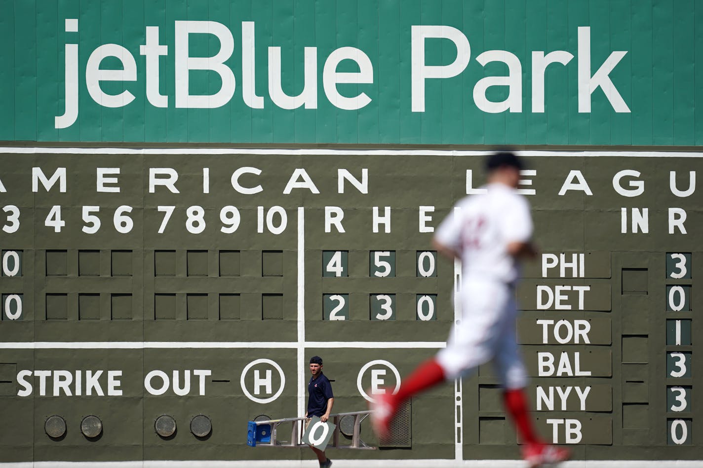 A Boston Red Sox worker watched players take the field after changing the manual score board at JetBlue Park during 2019 spring training.