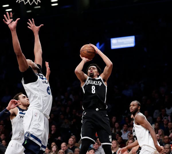 Brooklyn Nets' Spencer Dinwiddie (8) shoots over Minnesota Timberwolves' Taj Gibson, left, and Andrew Wiggins, right, during the second half of an NBA