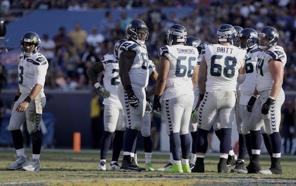 Seattle Seahawks quarterback Russell Wilson, left, pulls out of the huddle during the first half in an NFL football game against the Los Angeles Rams 