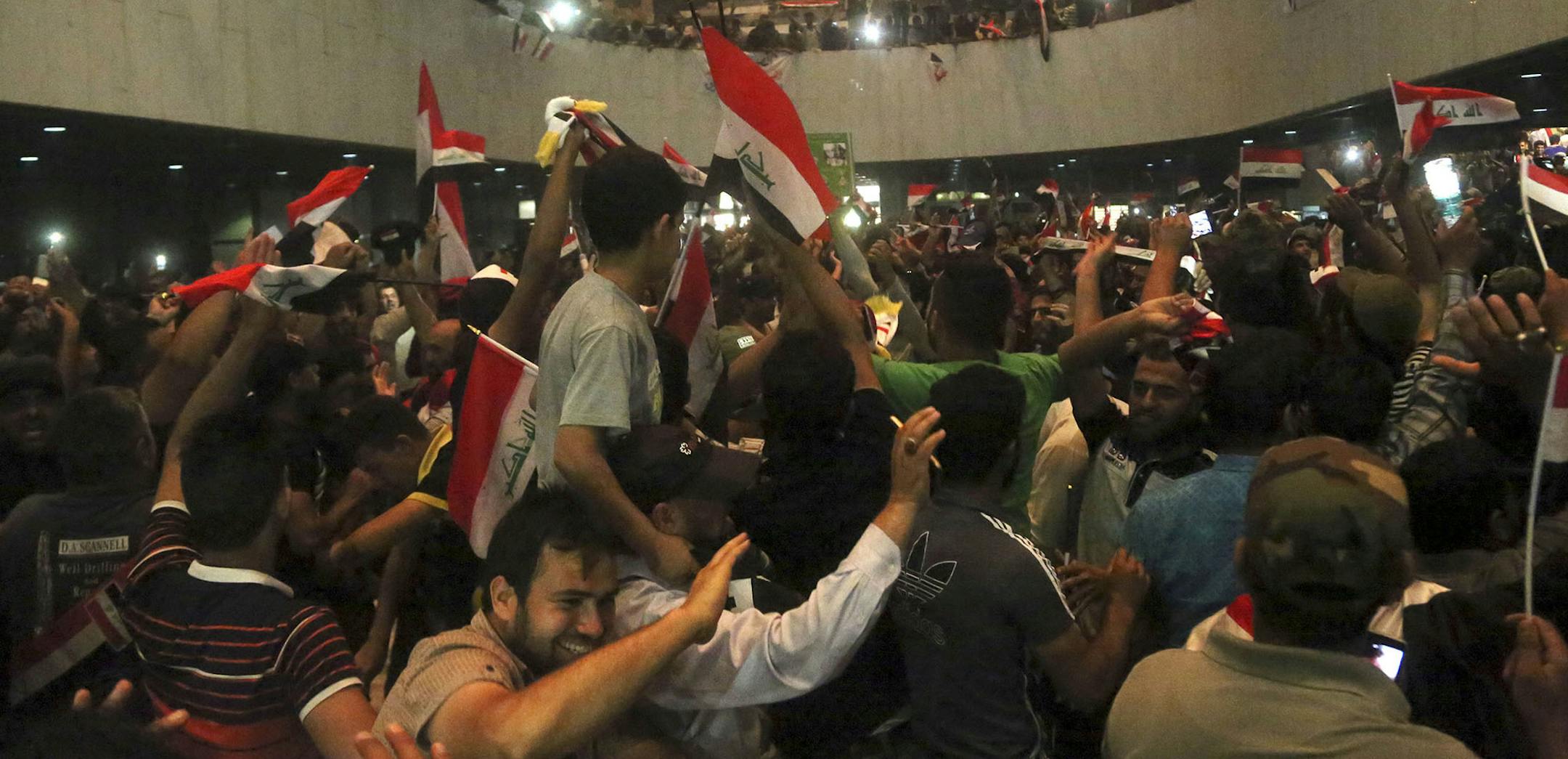 Supporters of Shiite cleric Muqtada al-Sadr storm parliament in Baghdad's Green Zone, Saturday, April 30, 2016. Dozens of protesters climbed over the blast walls and could be seen storming the Parliament building, carrying Iraqi flags and chanting against the government. (AP Photo/Khalid Mohammed) ORG XMIT: MIN2016050314112355