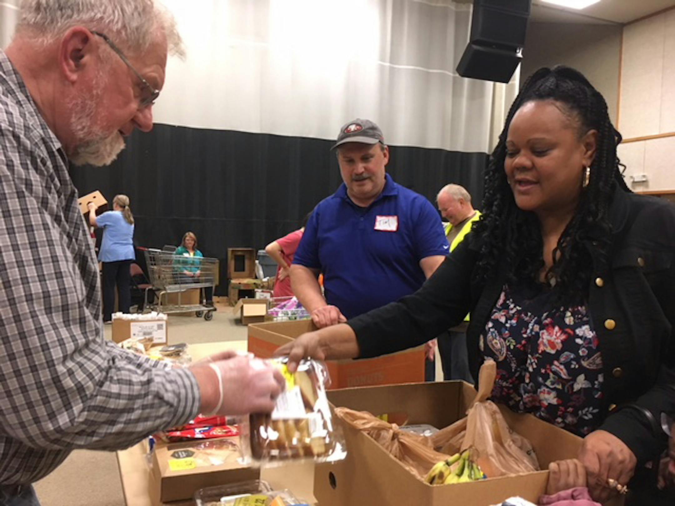 Marquita Mosby, right, shops at Revive's food center, assisted by Dave Aanerud, left, and Mike Langhus, center.
