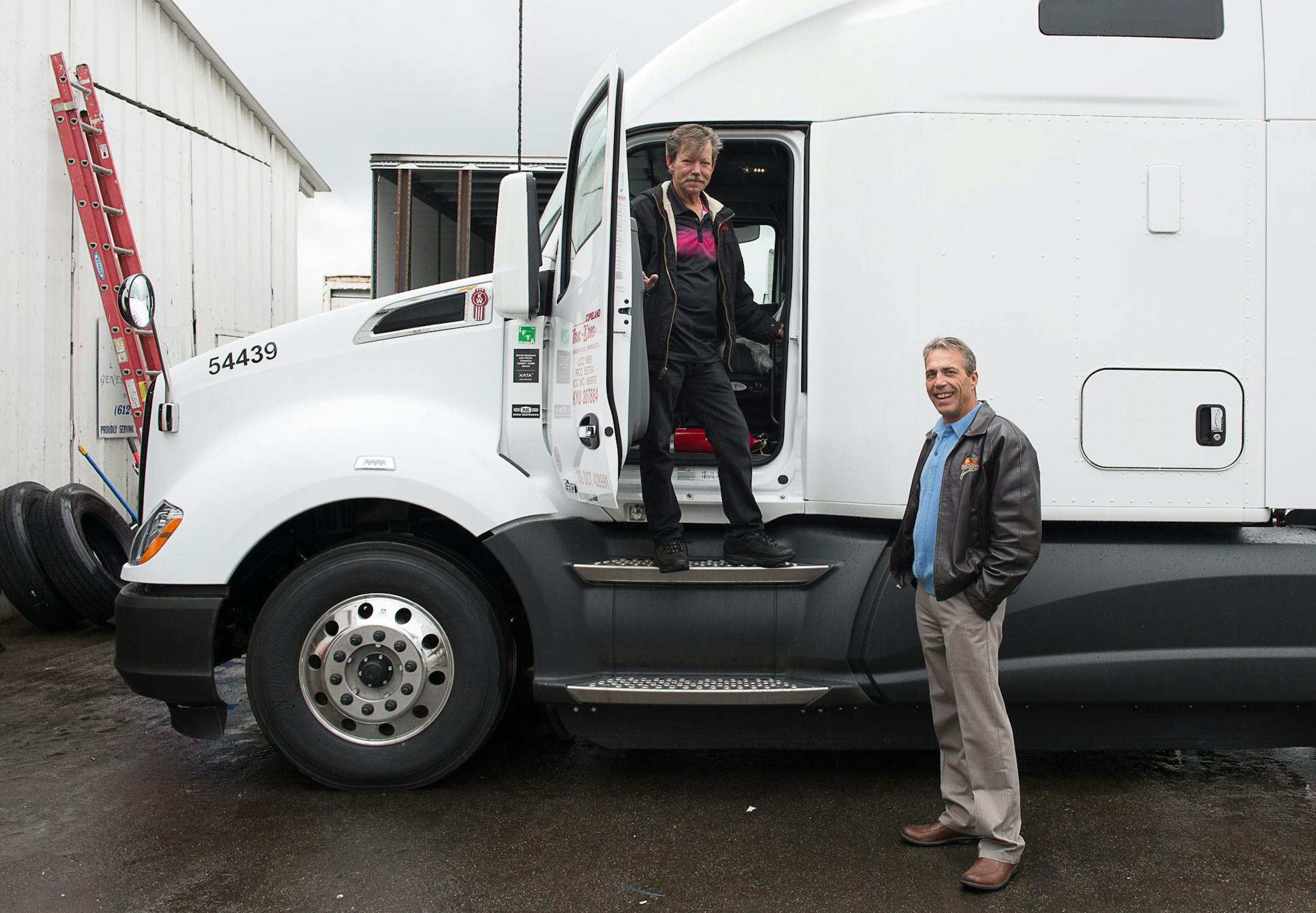 Truck driver Driver Bill McMahon, who was recently rehired by his former employer Copeland Trucking (co-owner Tim Hoag, McMahon's boss is at right) prepares to depart soon in a brand new $145,000 rig from the company's location in Fridley, Minnesota on October 2, 2014. [ Angela Jimenez/Special to the Star-Tribune angelajime@gmail.com Assignment #20036493A_ SLUG: TRUCK100514_ EXTRA INFORMATION: Minnesota's severe trucker shortage is forcing wages up and creating accommodating working conditions f
