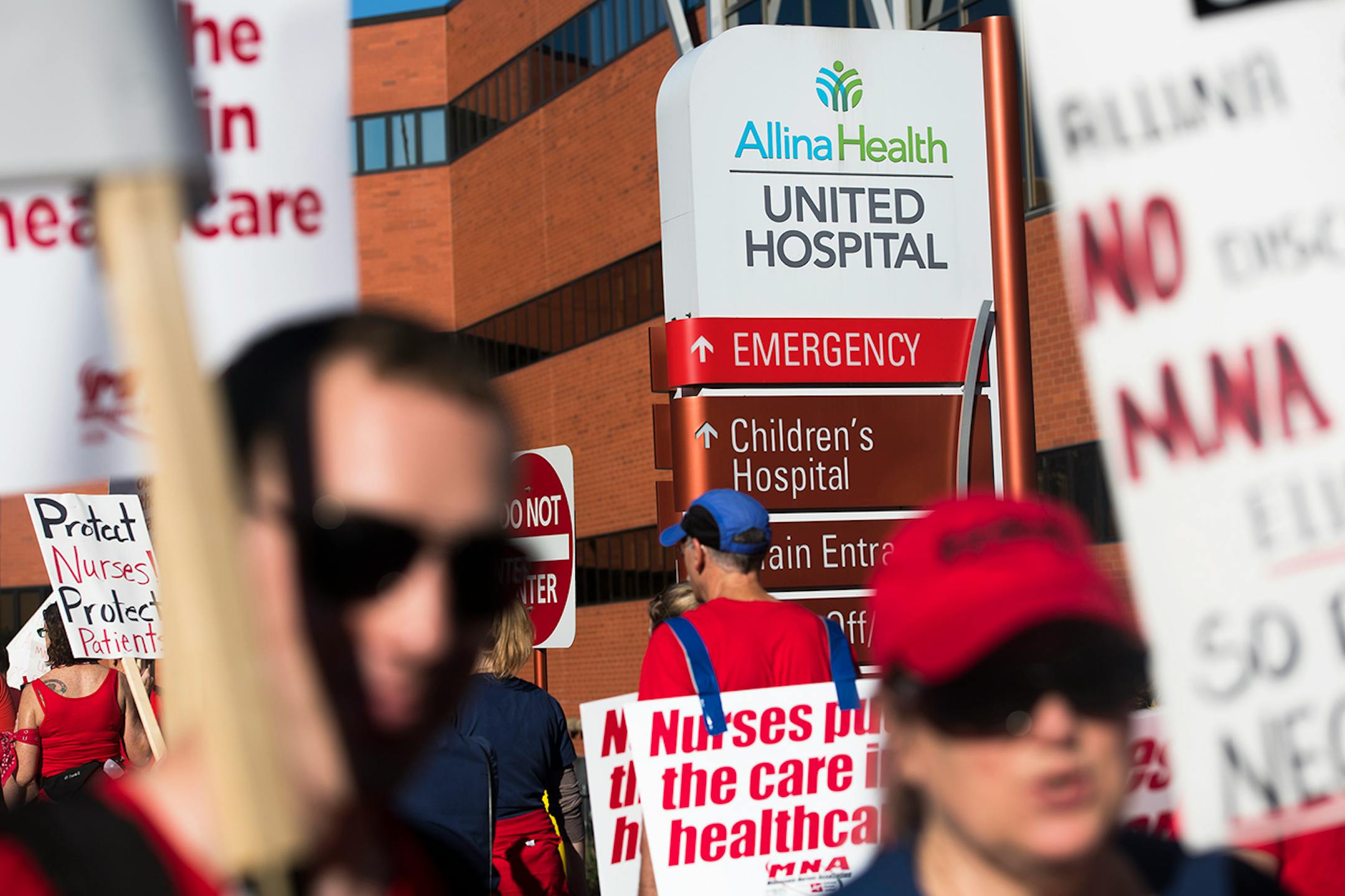 Picketers walk with signs in front of United Hospital in St. Paul. Pickets will continue from 7 a.m. to 7 p.m. today.