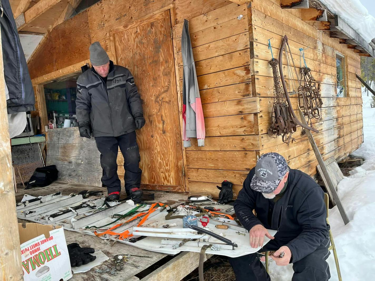 Operating without a follow-along support crew, the three "old guy'' snowmobilers brought excess parts with them, and are shown here in Old Crow, Yukon, assessing their machines' needed maintenance.