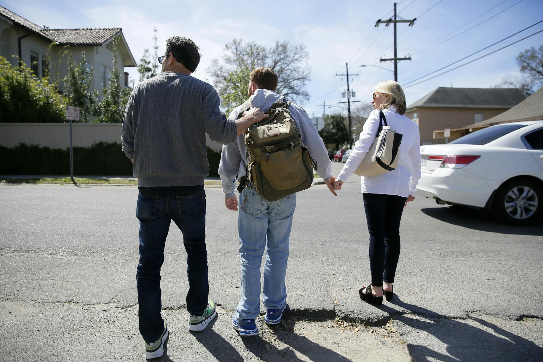 ADVANCE FOR USE SUNDAY, APRIL 24, 2016 AND THEREAFTER -In this Wednesday, March 2, 2016 photo, Sam Alexander and Ellen Schneider help their son, Ben, cross a street on their way to lunch in New Orleans. When Alexander was about 2 1/2 he was diagnosed with autism. Often called pervasive developmental disorder, it was accompanied by epileptic episodes, which worsened in adolescence, as did some of his erratic behavior. (AP Photo/Jonathan Bachman)
