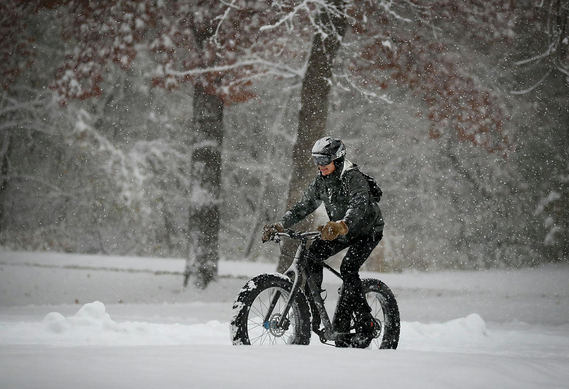 A bicyclist rides on fresh snow while biking along Lake Harriet Tuesday in Minneapolis.