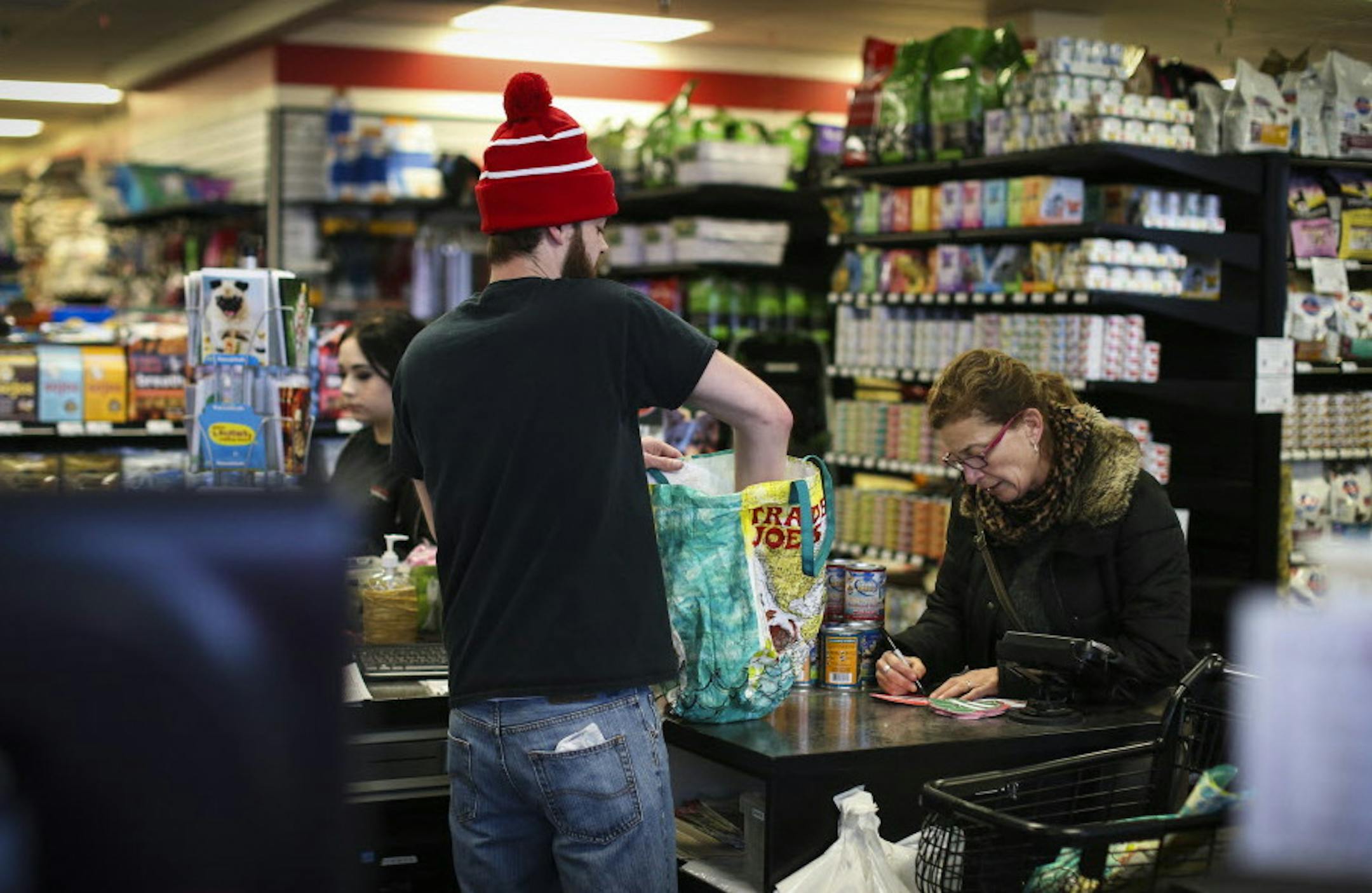 Evan Carlson bagged Jodi Davis' cat food as she filled out a Paw Print Fundraiser card at Chuck and Don's Pet Food and Supplies in Minneapolis, Minn. on Friday, December 19, 2014. ] REN&#xc9;E JONES SCHNEIDER reneejones@startribune.com