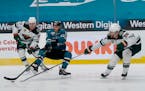 San Jose Sharks right wing Kevin Labanc, middle, reaches for the puck between Minnesota Wild left wing Kirill Kaprizov (97) and defenseman Ian Cole (2