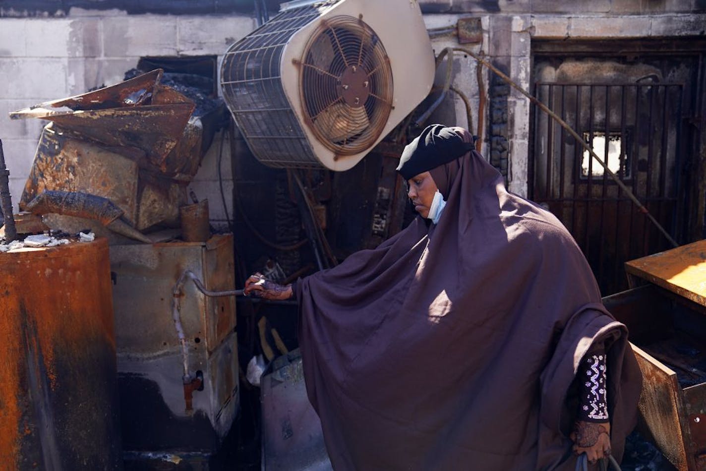 Kaltuma Hassan, who lost the Bismillah Grocery & Coffee shop during the riots, looked around the charred remains of her store as she revisited the scene Thursday.