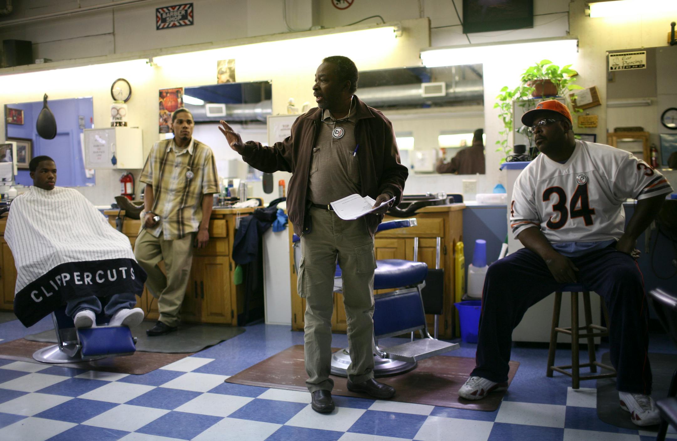 Sunday Alabi, ACORN Minnesota's PAC coordinator, spoke at an informational ACORN meeting at Clipper Cuts barber shop in Minneapolis on Monday evening. Barbers Ty McCoy, left, giving Donald Williams a trim, and William Hambrick signed up to volunteer with ACORN.