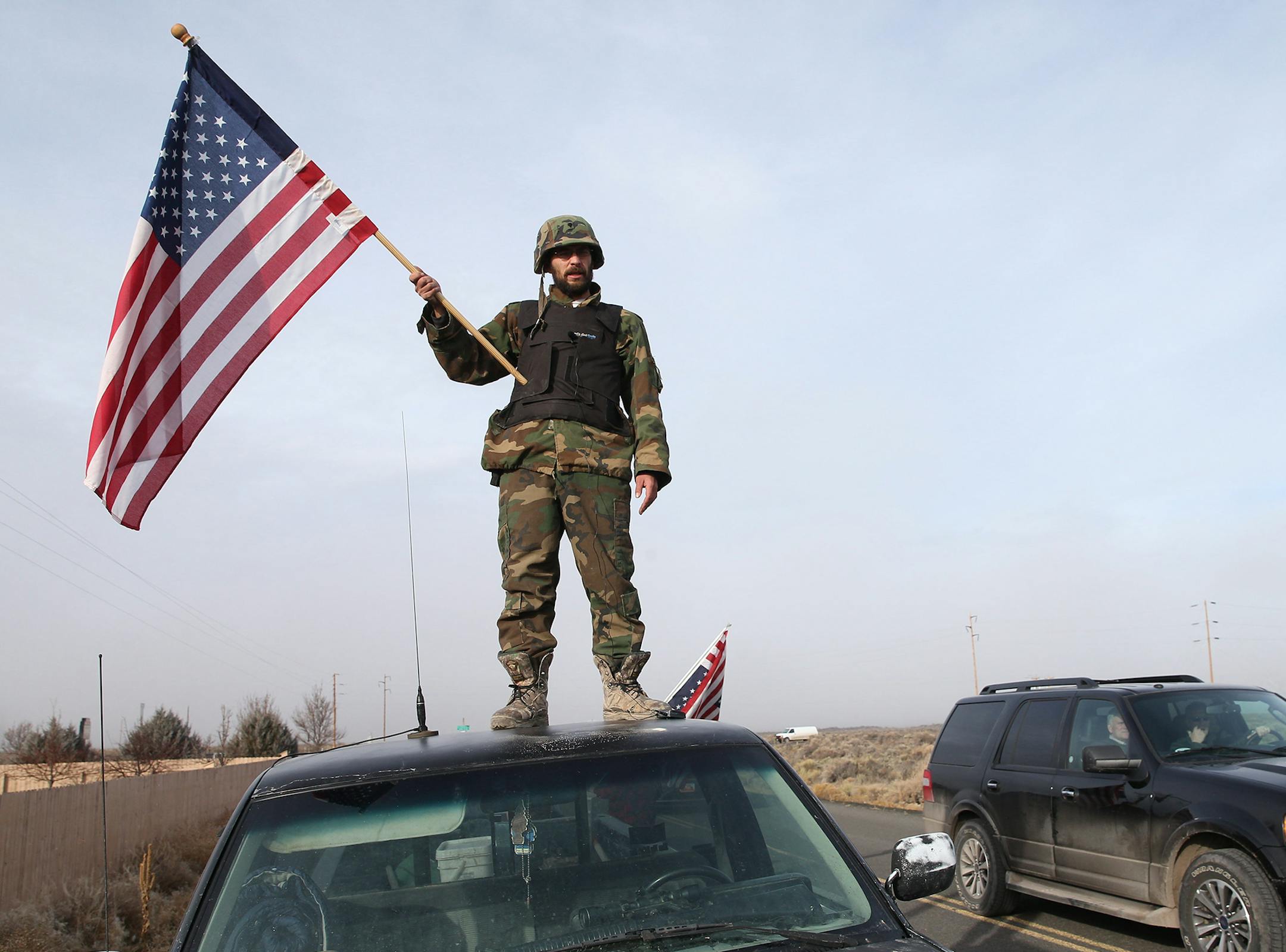 A man wave American flag from atop a car at the Narrows roadblock, Thursday, Feb. 11, 2016, near Burns, Ore. The last four occupiers of a Malheur National Wildlife Refuge in eastern Oregon surrendered Thursday. The holdouts were the last remnants of a larger group that seized the wildlife refuge nearly six weeks ago, demanding that the government turn over the land to locals and release two ranchers imprisoned for setting fires. (Thomas Boyd/The Oregonian via AP) MAGS OUT; TV OUT; NO LOCAL INTER