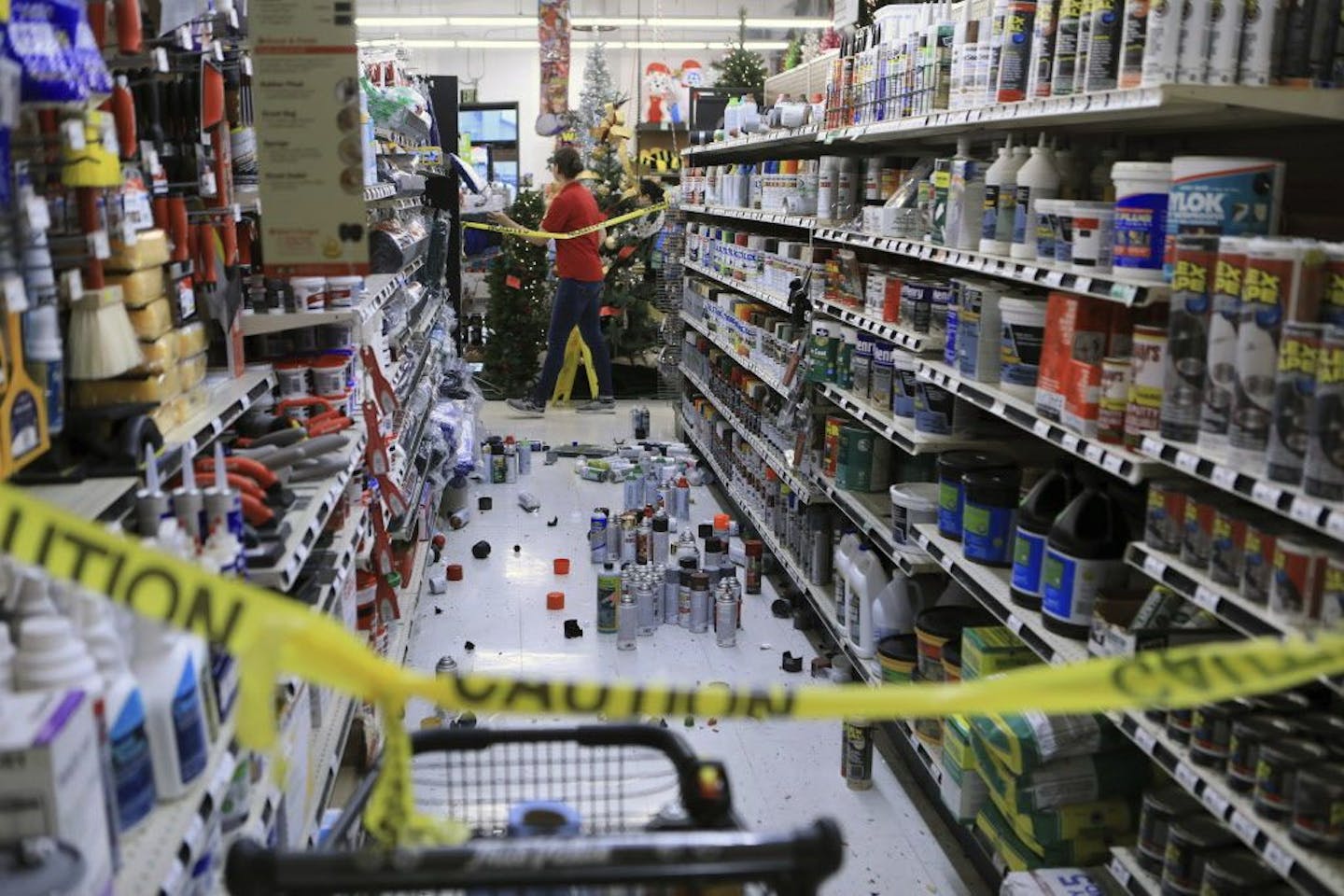 An employee walks past a damaged aisle at Anchorage True Value hardware store after an earthquake, Friday morning, Nov. 30, 2018, in Anchorage, Alaska. Tim Craig, owner of the south Anchorage store, said no one was injured but hundreds of items hit the floor and two shelves collapsed in a stock room.