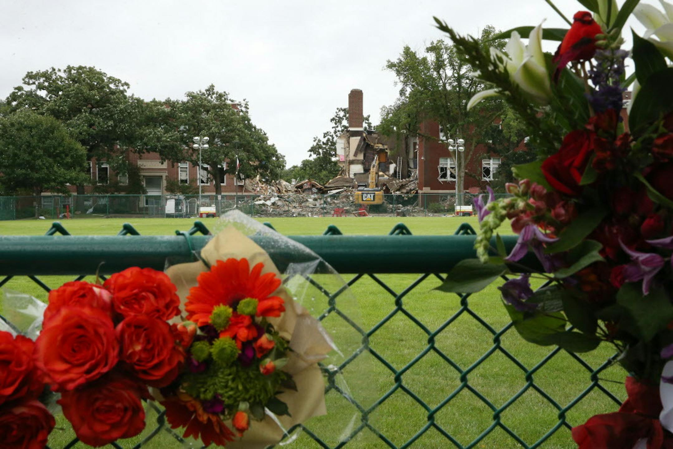 Community members left flowers in the fence at a make-shift memorial near the scene. ] ANTHONY SOUFFLE ï anthony.souffle@startribune.com Minneapolis police, NTSB investigators, and community members look over the aftermath of a gas explosion at Minnehaha Academy Thursday, August 3, 2017 in Minneapolis.