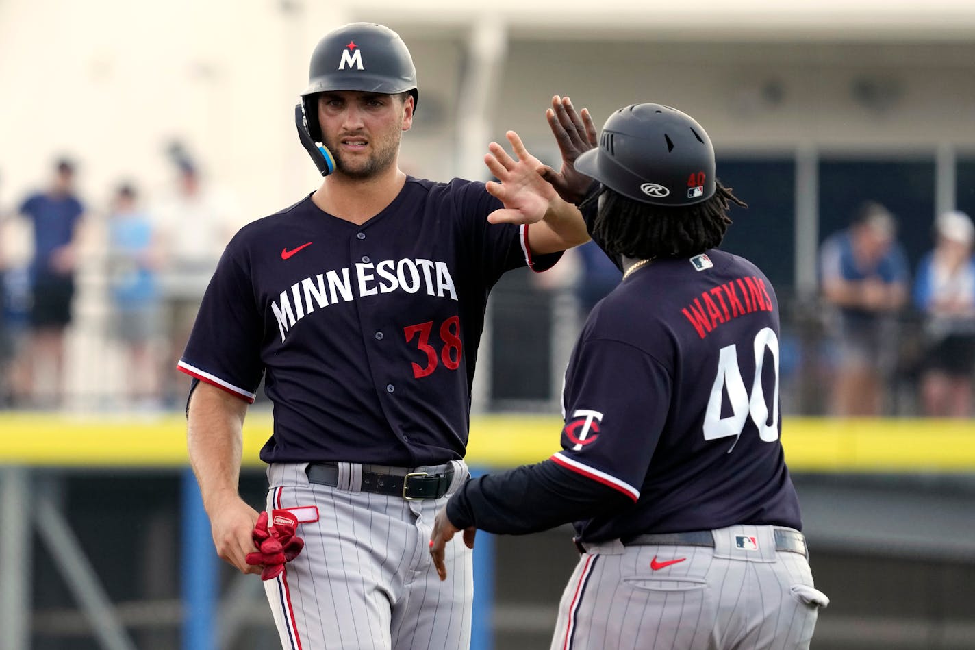 Minnesota Twins' Matt Wallner (38) high fives third base coach Tommy Watkins (40) after his Rbi double off Toronto Blue Jays starting pitcher Alek Manoah during the fourth inning of a spring training baseball game Wednesday, March 8, 2023, in Dunedin, Fla. (AP Photo/Chris O'Meara)