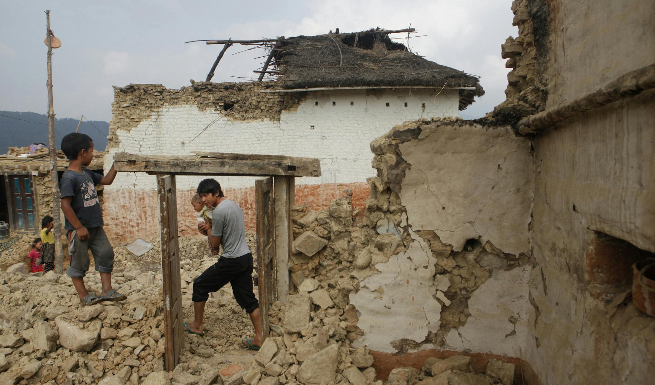 Nepalese people stand by damaged homes in Lalitpur, Nepal, Friday, May 8, 2015. The April 25 earthquake killed thousands and injured many more as it flattened mountain villages and destroyed buildings and archaeological sites in Kathmandu. (AP Photo/Niranjan Shrestha)