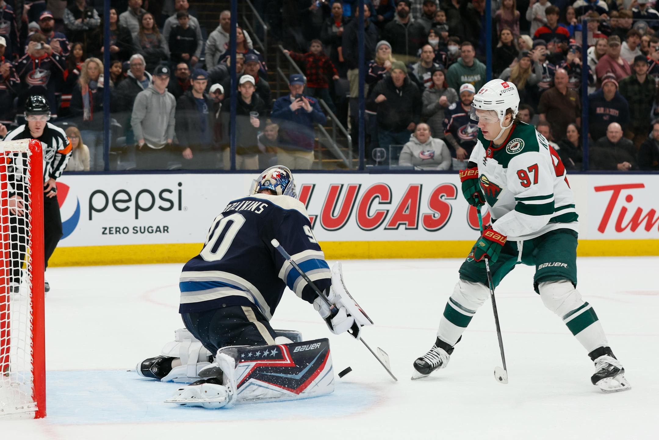 Columbus Blue Jackets' Elvis Merzlikins, left, makes a save against Minnesota Wild's Kirill Kaprizov during a shootout in an NHL hockey game, Friday, March 11, 2022, in Columbus, Ohio. (AP Photo/Jay LaPrete)