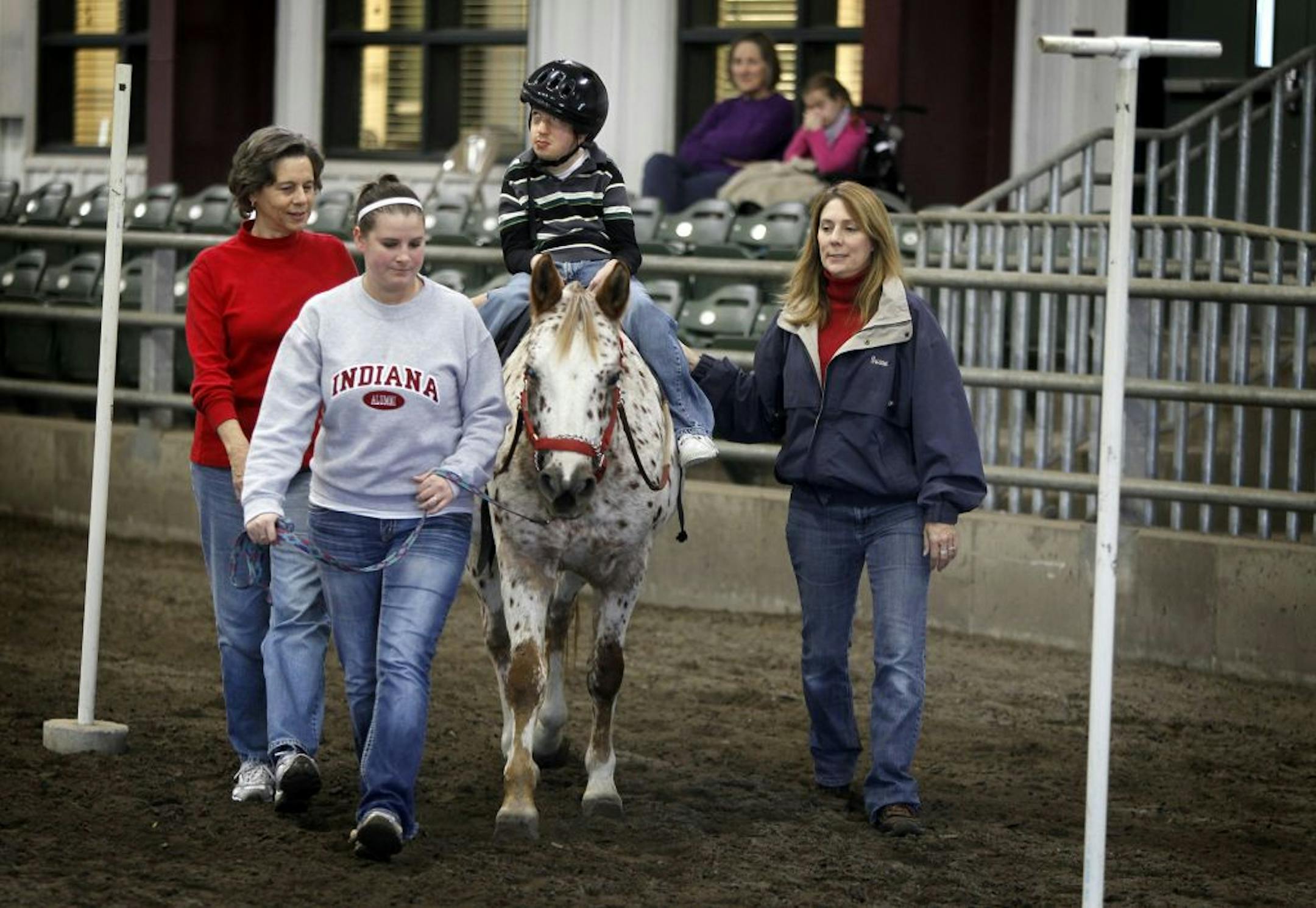 Volunteers Gail Streitz, left, Taylor Gause and Susan Vince worked with cerebral palsy client Steven Becker at the U of M's Equine Center on Tuesday.