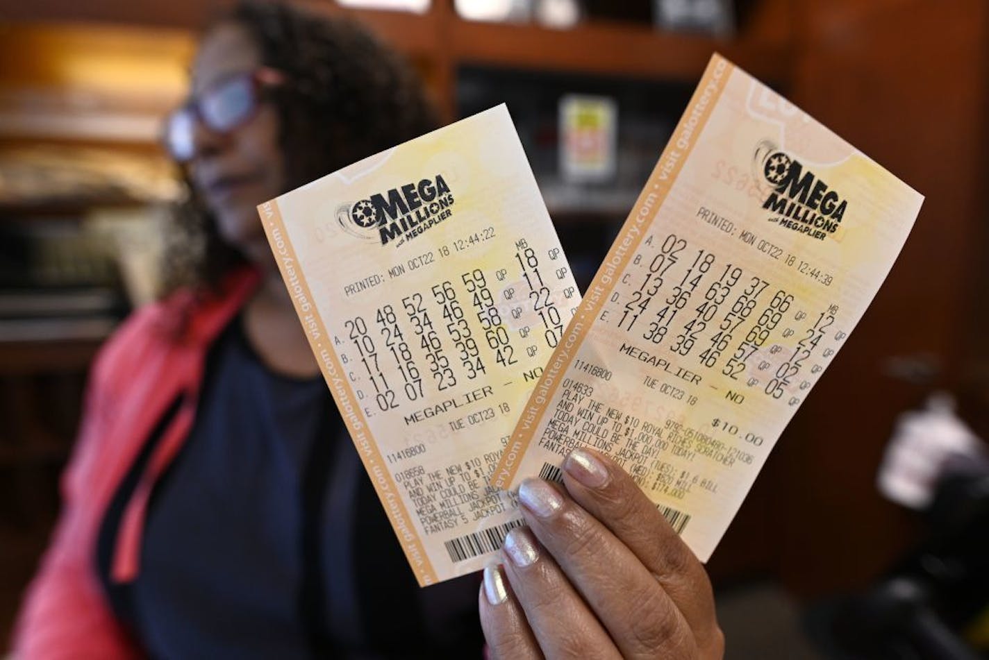 A shop employee in Atlanta holds Mega Millions lottery tickets, Monday, Oct. 22, 2018. No one won the $1 billion jackpot in Saturday night's drawing, which means the top prize for Tuesday night's Mega Millions drawing would be the largest lottery jackpot in U.S. history.