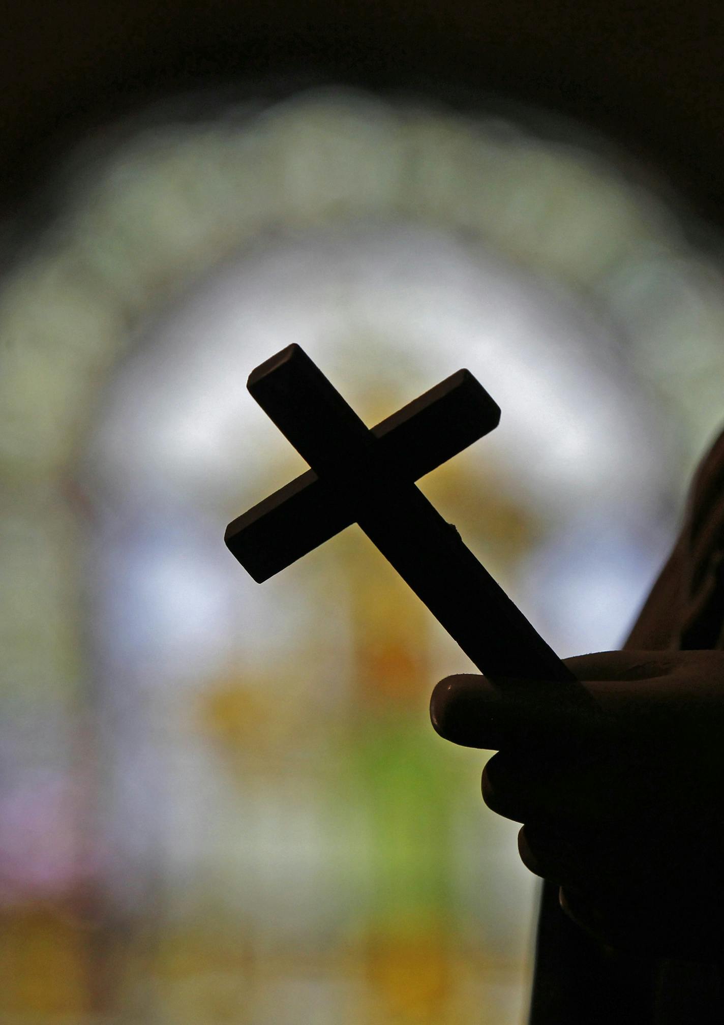 FILE - This Dec. 1, 2012 file photo shows a silhouette of a crucifix and a stained glass window inside a Catholic Church in New Orleans. As U.S. Catholic bishops gather for an important national assembly, the clergy sex abuse crisis dominates their agenda. But it's only one of several daunting challenges facing the nation's largest religious denomination. While federal and state law enforcement agencies widen their investigations of abuse, the church finds itself with ever fewer priests and nuns