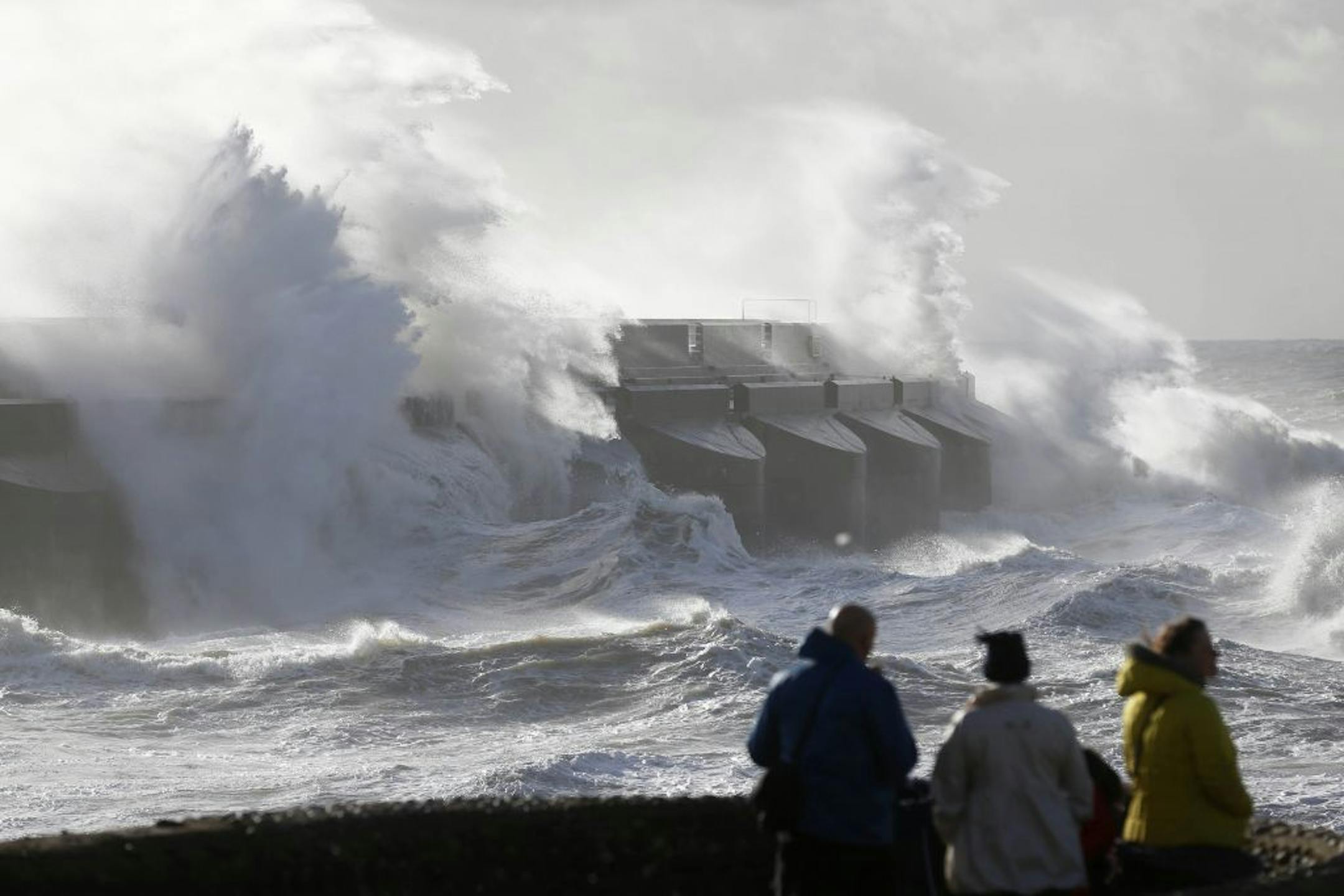 People watch the waves batter into the sea wall of a marina in Brighton, south England, Monday, Oct. 28, 2013. A major storm with hurricane force winds is lashing much of Britain, causing flooding and travel delays including the cancellation of roughly 130 flights at London's Heathrow Airport. Weather forecasters say it is one of the worst storms to hit Britain in years.