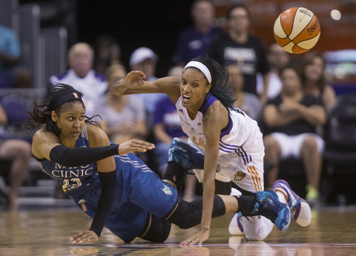 Minnesota Lynx's Maya Moore, left, grabs a loose ball and makes a pass falling around Phoenix Mercury's DeWanna Bonner during Game 2 of the WNBA basketball Western Conference finals, Sunday, Sept. 27, 2015, in Phoenix. (Patrick Breen/The Arizona Republic via AP)